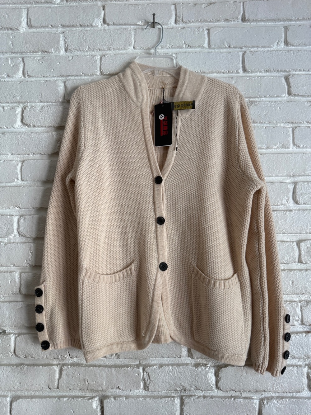 Cream cardigan with black buttons and pockets